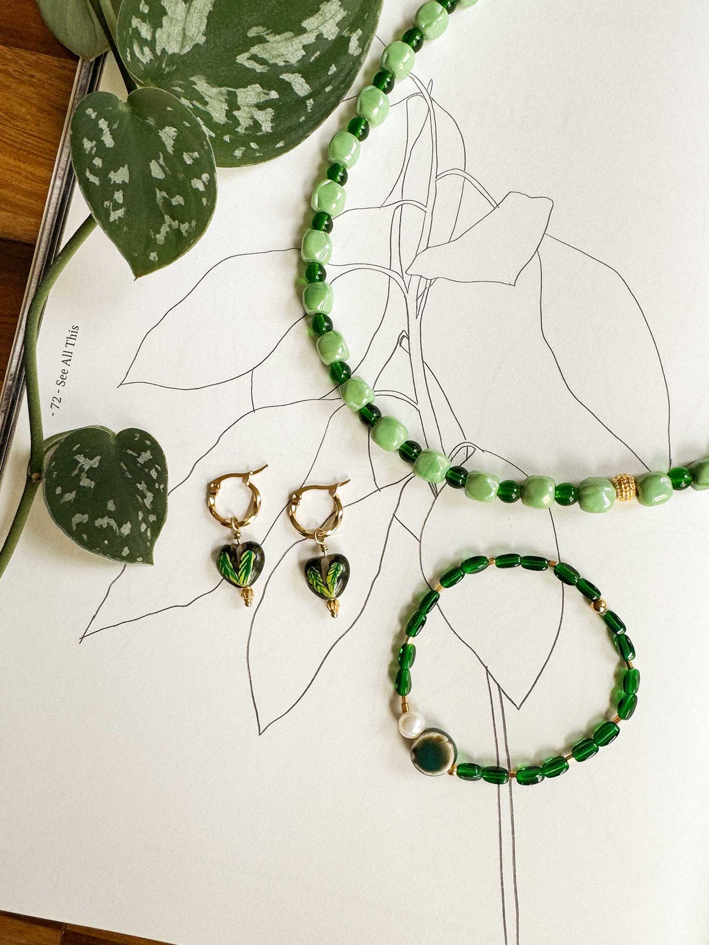 Statement ketting met groene kralen, groene hartjes oorbellen en armband flatlay
