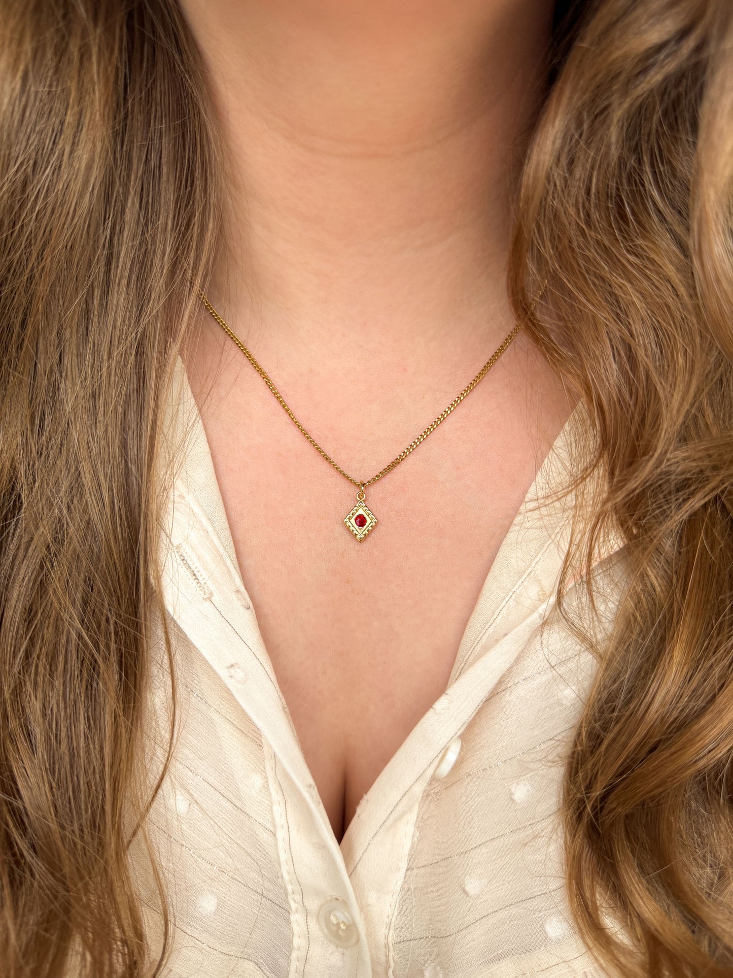 Gouden bedelketting met rood steentje