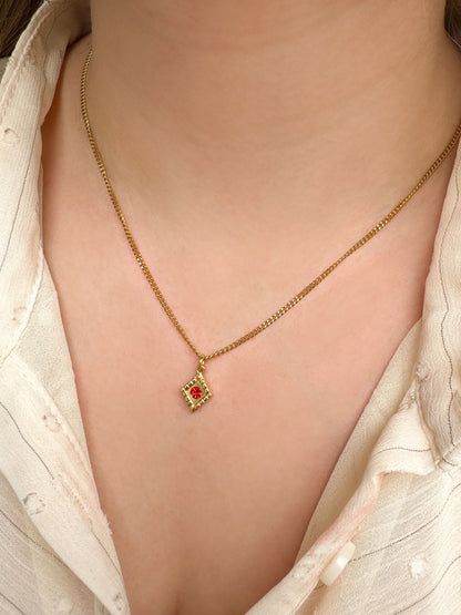 Gouden ketting met ruitjes bedel en rood steentje