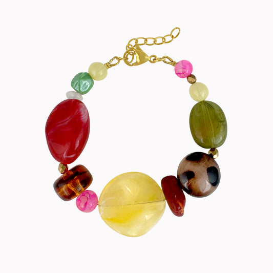 Kleurrijke statement kralenarmband met grote rode, gele, groene, roze en bruine kralen en gouden sluiting.