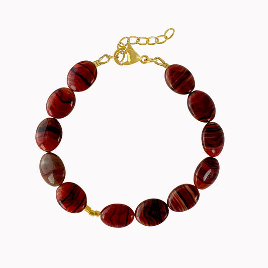 Rode kralenarmband met glanzende ovale kralen met donkere strepen en kleine gouden accenten.
