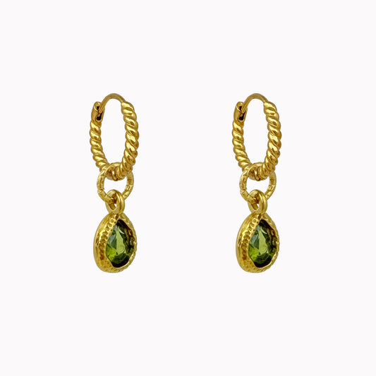 Gedraaide gouden oorringen met kleine groene druppelvormige stenen in een goudkleurige zetting.