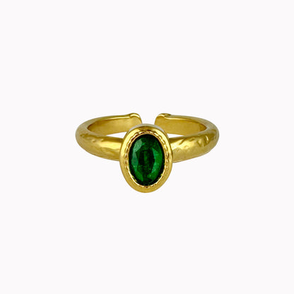 Gouden verstelbare ring met ovale donkergroene steen en een licht gehamerde afwerking.