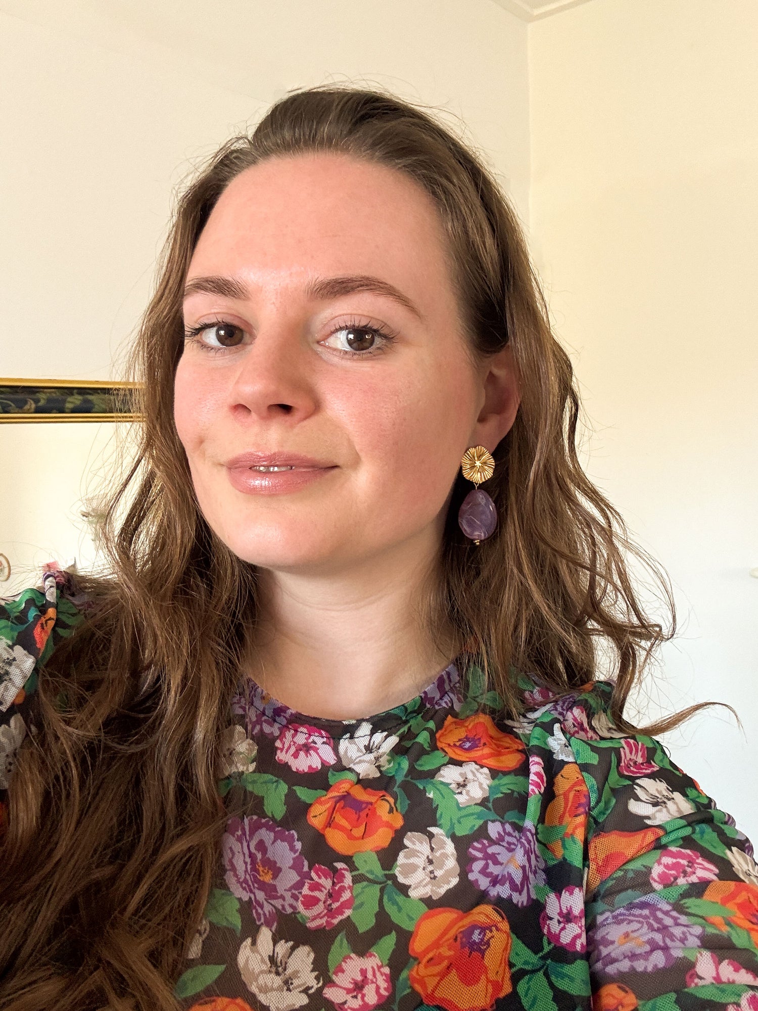 Model met gouden statement oorbellen met een paarse steen