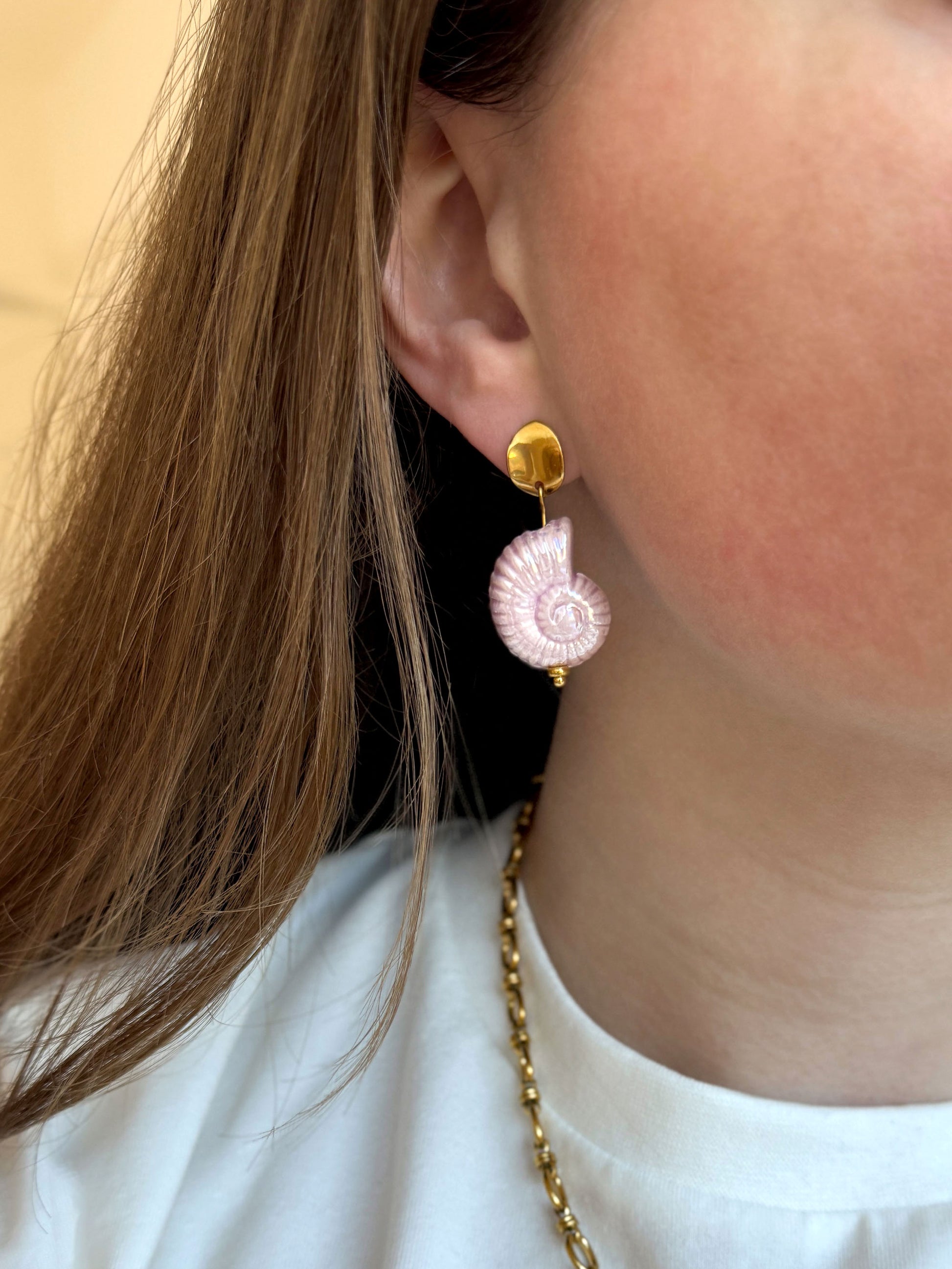 Close-up gouden oorhanger met roze schelp van keramiek
