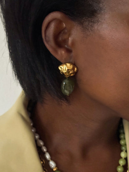Close-up van een vrouw met gouden statement oorbellen met een donkergroene kraal uit de Atelier Colore collectie van Don’ aparte.