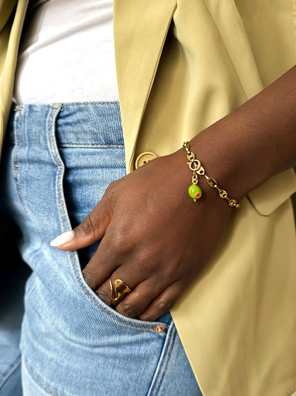 Vrouw draagt een gouden schakelarmband met groene olijfbedel en een gouden organische statement ring van Don’ aparte